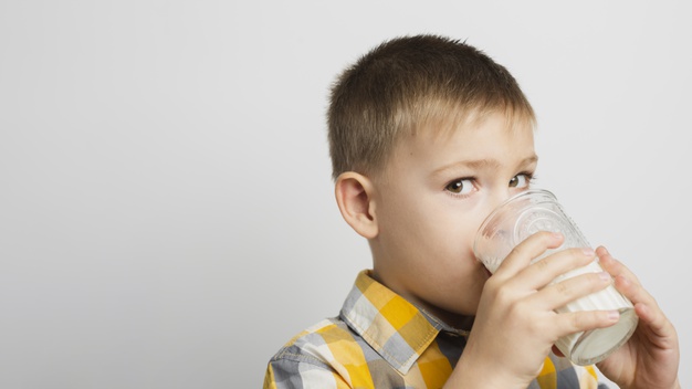 Criança bebendo leite com cara de desconfiada